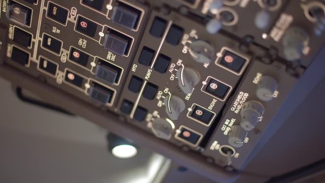 Jumbo jet pilot's hand turns and presses overhead switches in a commercial airplane cockpit.  Originally recorded in 4K.