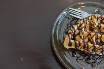waffle ,chocolate topping on black plate , wooden black background