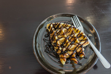 waffle ,chocolate topping on black plate , wooden black background