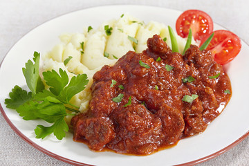 Goulash with mashed potatoes and tomato
