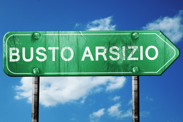 Busto Arsizio road sign, vintage green with clouds background