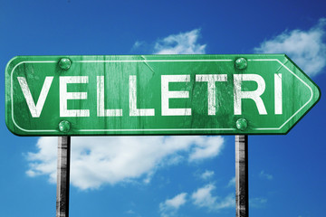 Velletri road sign, vintage green with clouds background