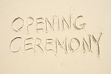 Fototapeta na wymiar Simple Opening Ceremony message handwritten on smooth sand beach