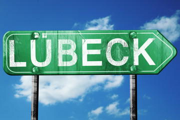 Lubeck road sign, vintage green with clouds background