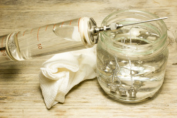 Iron vintage glass syringe with needles on a wooden background.