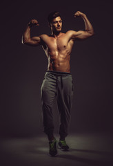 Obraz na płótnie Canvas Athletic handsome man showing biceps muscles, studio shot