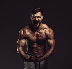 Fototapeta na wymiar Athletic handsome man showing biceps muscles, studio shot
