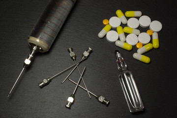Medical syringe and pills on dark background
