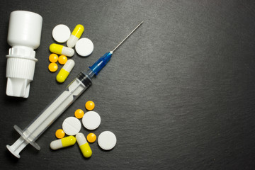 Medical syringe and pills on dark background