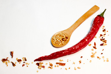 Red chili pepper and seeds in wooden spoon on white background