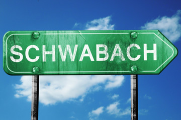 Schwabach road sign, vintage green with clouds background