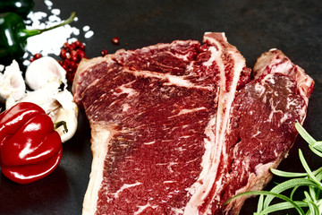 Raw aged steak and seasoning on dark background