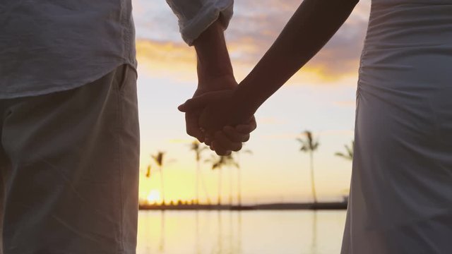 Romantic couple holding hands on beach at sunset
