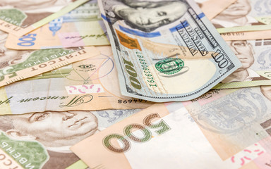 One hundred dollar bill on the background of the Ukrainian hryvn