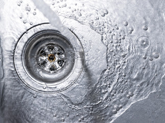 Running water drains down a stainless steel sink - 108886226