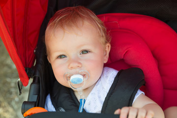 Baby with a pacifier in a stroller