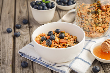 Homemade granola with blueberries on rustic background, selective focus, copy space