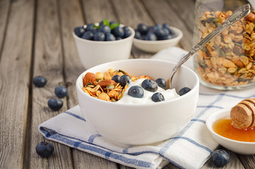 Homemade granola with blueberries on rustic background, selective focus, copy space