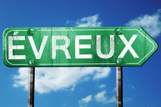 Evreux road sign, vintage green with clouds background