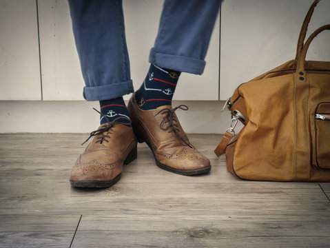Fashion man legs in indigo navy blue pants, navy anchor socks, leather shoes and leather tote bag ( Vintage tone color )