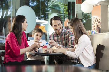 Family Having Ice Creams At Table In Parlor