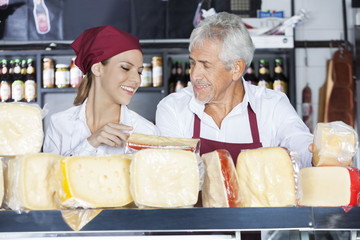 Colleagues Discussing While Holding Cheese In Store