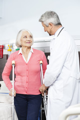 Senior Patient Being Assisted By Doctor With Crutches