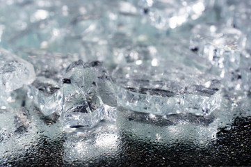 pile of different ice cubes on reflection table with water drops