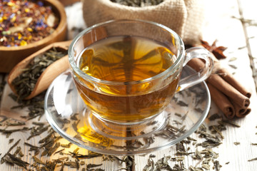 Cup of tea and mix of assorted tea leaves on wooden table