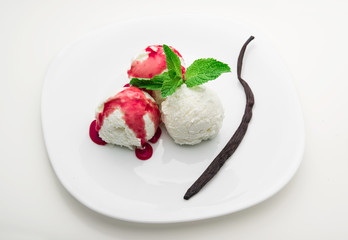 Three scoops of vanilla ice cream with strawberry syrup and mint on a white plate and a vanilla bean, white background