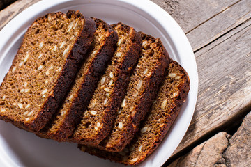 Slices of bread on plate. Brown bread on wooden background. Work of skillful baker. Simple snack that gives energy.