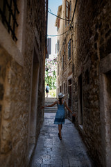 Fototapeta na wymiar Girl goes on a narrow alley between the houses