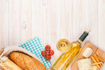 White wine, cheese and bread on white wooden table background