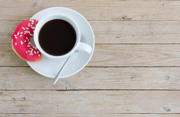 Cup of coffee with a half donut, top view.