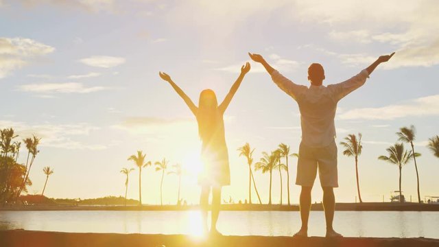 Serene happy couple enjoying nature sunset raising arms to the sky enjoying freedom and wellbeing feeling bliss and freedom. Woman and man enjoying amazing sunset together.