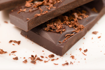 Pieces from a chocolate bar and chocolate crumbs on a white back