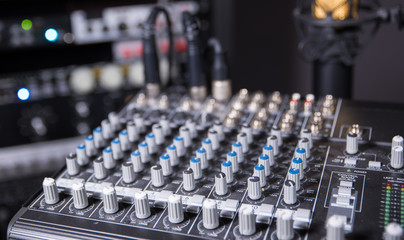 Artistic shot of recording studio mixing board and equipment in the background.