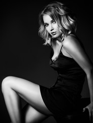 Fototapeta na wymiar Sexy blond woman in black silk lingerie over dark background.
