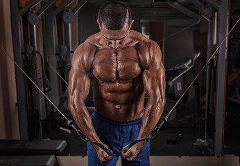 Naklejka na ściany i meble handsome bodybuilder works out pushing up exercise in gym