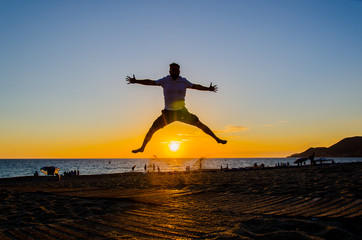 Freudensprung am Strand bei Sonnenuntergang