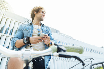 Handsome young man listening music with mobile phone and fixed g