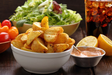 Roasted potatoes with dip and fresh salad on wooden table