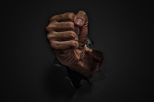 Power Concept. Man Fist Punching Through Black Paper