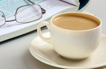 Cup of coffee near the laptop and newspapers