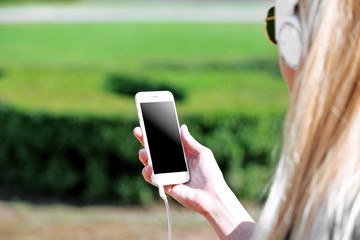 Young woman listening to music and walking along the street