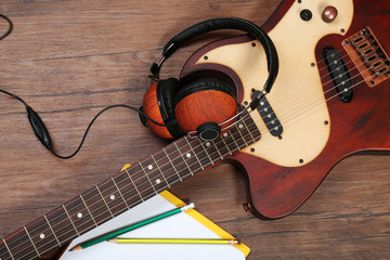 Naklejka premium Electric guitar and headphones on wooden background