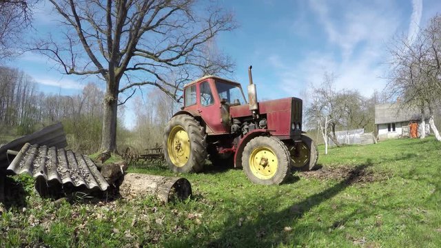 Old tractor in the homestead on sunny spring day, time lapse 4K

