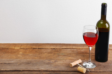 Wine and grape on wooden table against light background