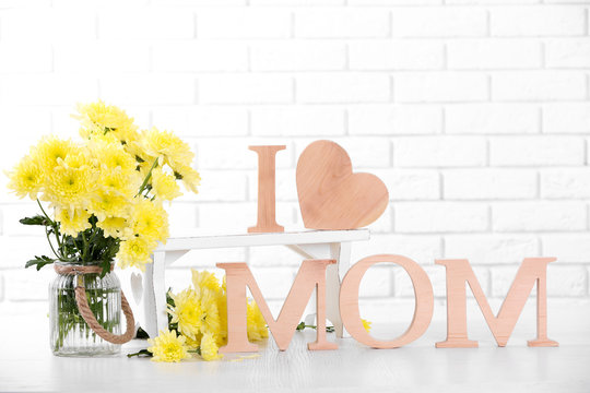 Wooden decor and flowers for mother's day on brick wall background