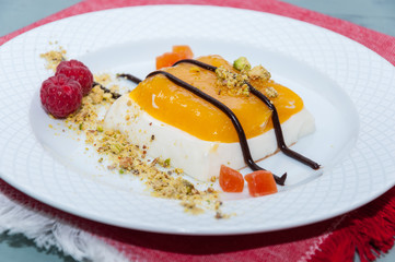 Postre italiano de panacota con mango y pistachos